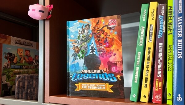 A photo of the official guide to Minecraft Legends sitting on a shelf alongside other Minecraft books and board games.