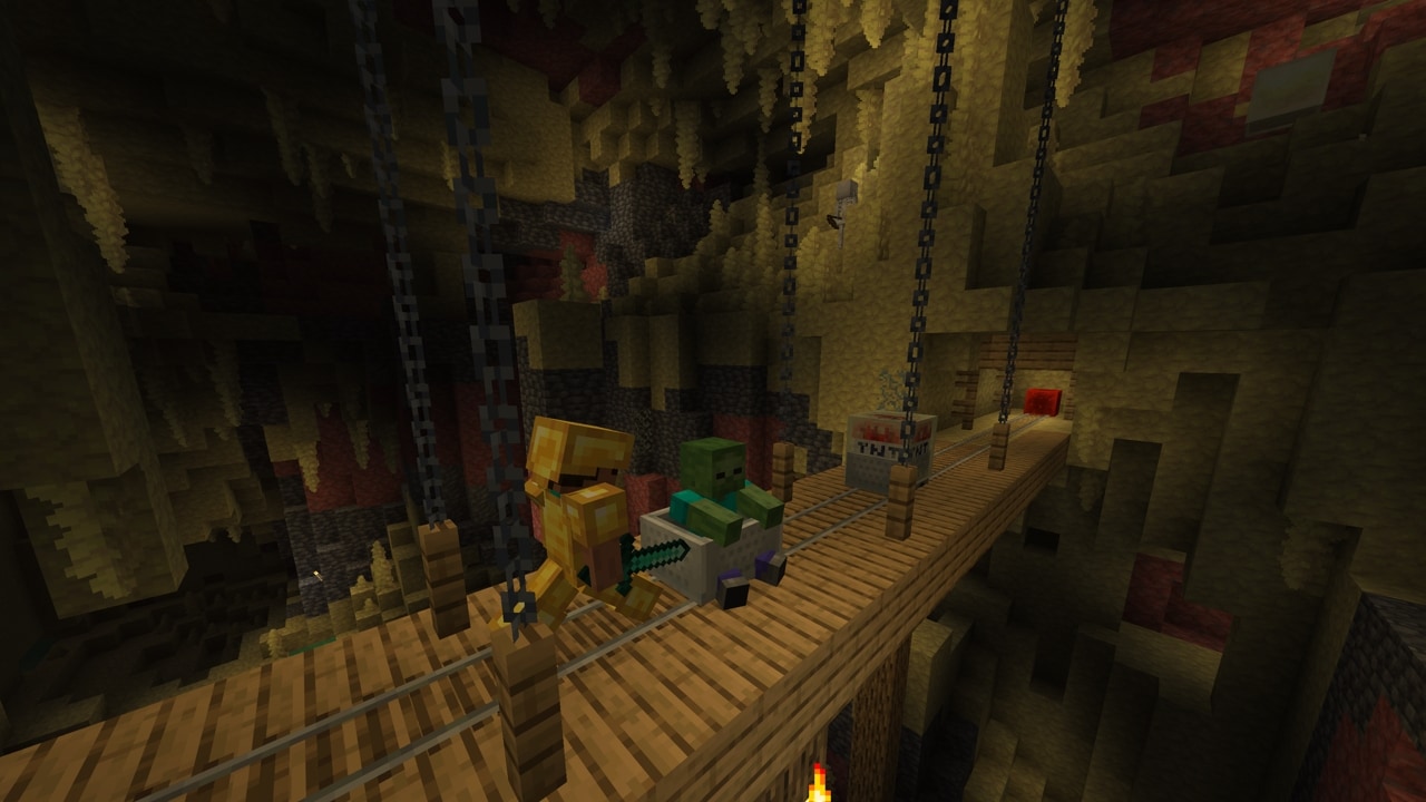 Steve pushing a Zombie in a minecart towards another minecart with TNT-absorbed Sulfur Cube on top of a mineshaft bridge with rails in a Sulfur Cave Biome.