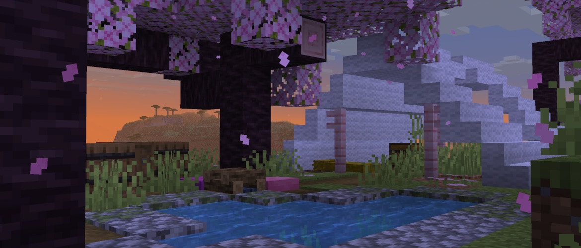 An abandoned campsite in a Cherry Grove biome with a small pool of water in the front. In the background, an orange sunset is visible.