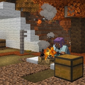 Efe is sitting on a cushion in front of a camp fire in an abandoned camp in a dappled forest.
