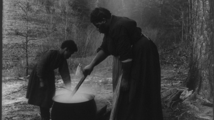 Two people standing over a cauldron.