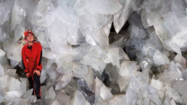 A photo of a person wearing safety gear, standing inside a white crystal cave.