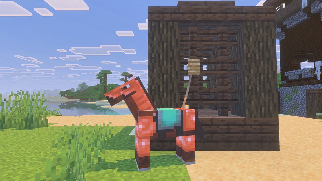 A copper-armoured horse stands beside a wooden stable on a sandy beach. The sky is bright, with trees and water in the background.