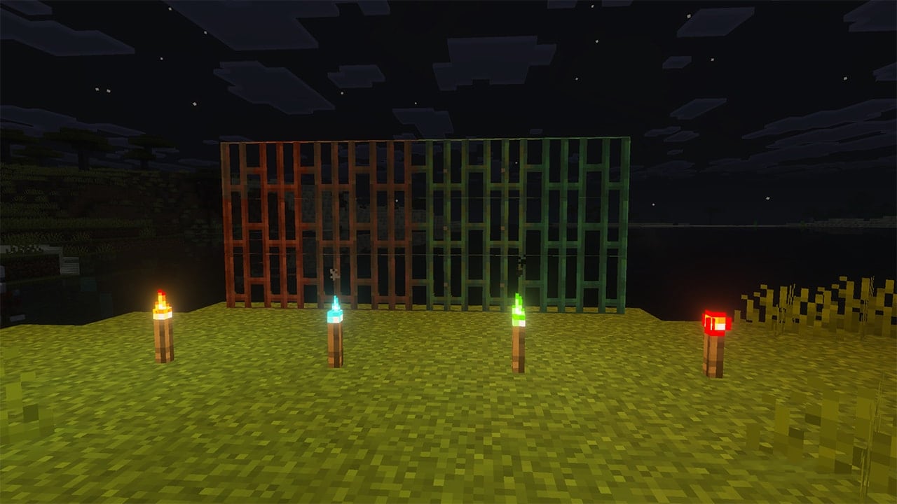 Copper bars of different oxidation stages stand on grass at night. Four torches glow in blue, green, and red, lighting the scene.