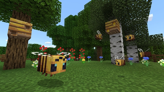 Multiple bees hover around their beehives, flowers and trees surround the area. 