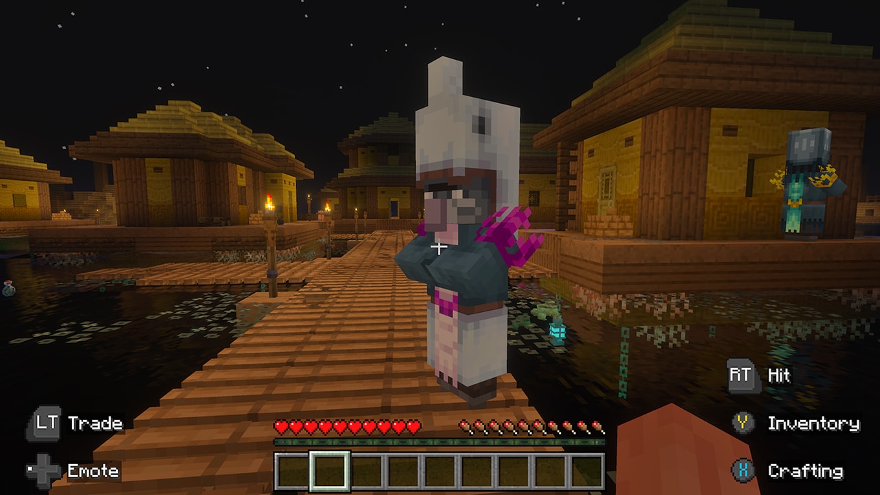 A villager wearing a fish-like helmet stands on a wooden dock in a stilt village at night, surrounded by water and glowing lanterns.