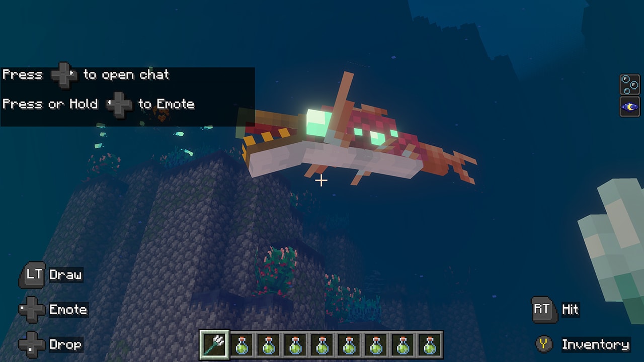 A large glowing fish swims above an underwater ruin covered in coral and sea plants as the player watches from below.