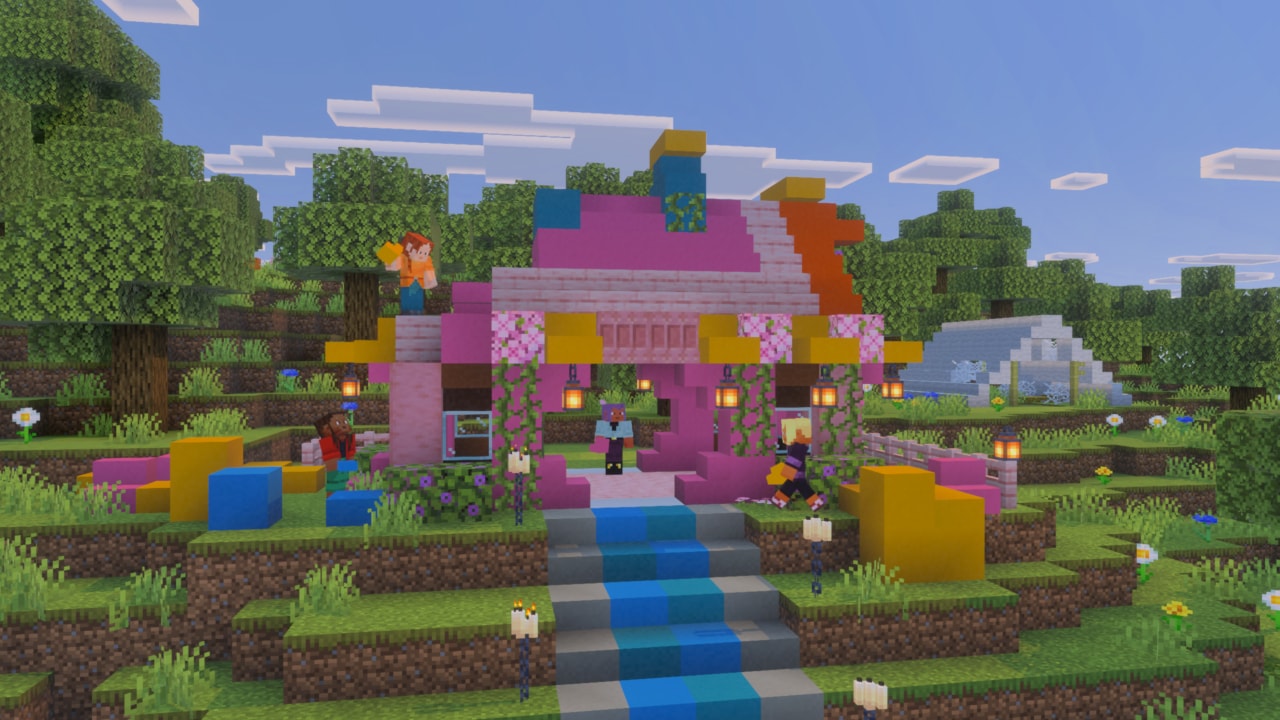 A colorful Minecraft house built from pink, blue, yellow, and orange blocks sits in a forest clearing as players gather around its lantern-lit entrance.