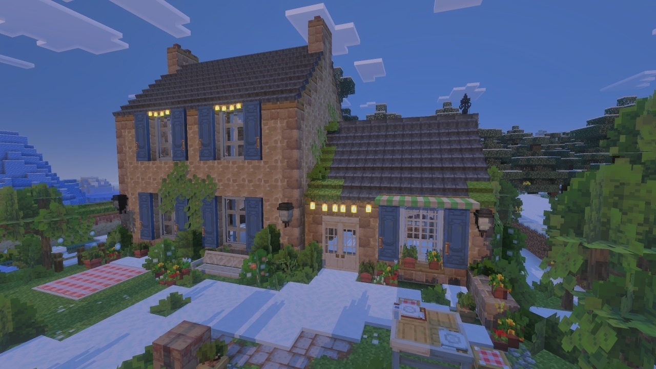 A cozy two story house with warm lights glowing stands among trees and gardens at dusk