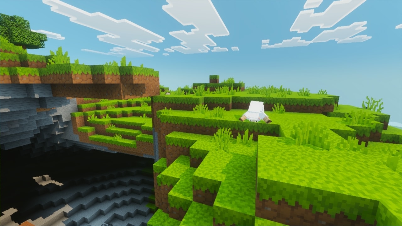 A blocky sheep grazes on bright green grass near the edge of a cliff overlooking a deep cave and rolling hills